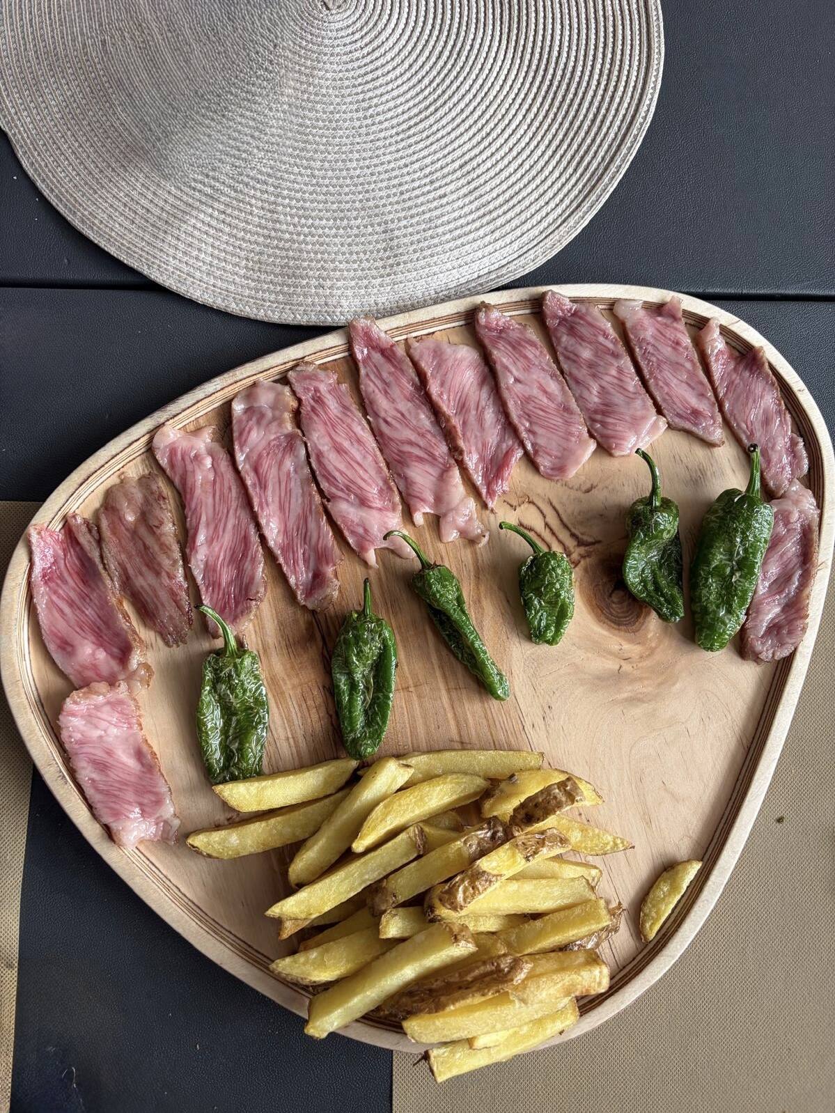 Wagyu japonés A5 al corte a la brasa con pimientos de padrón y patatas en Con Acento Parrilla, Córdoba